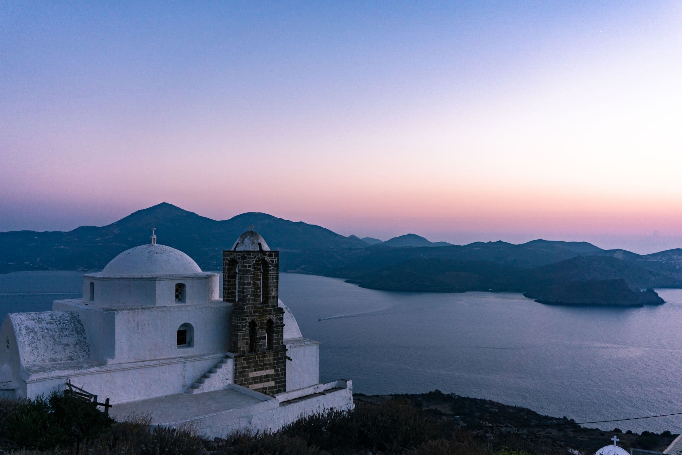 White church on Milos overlooking the sea at sunset